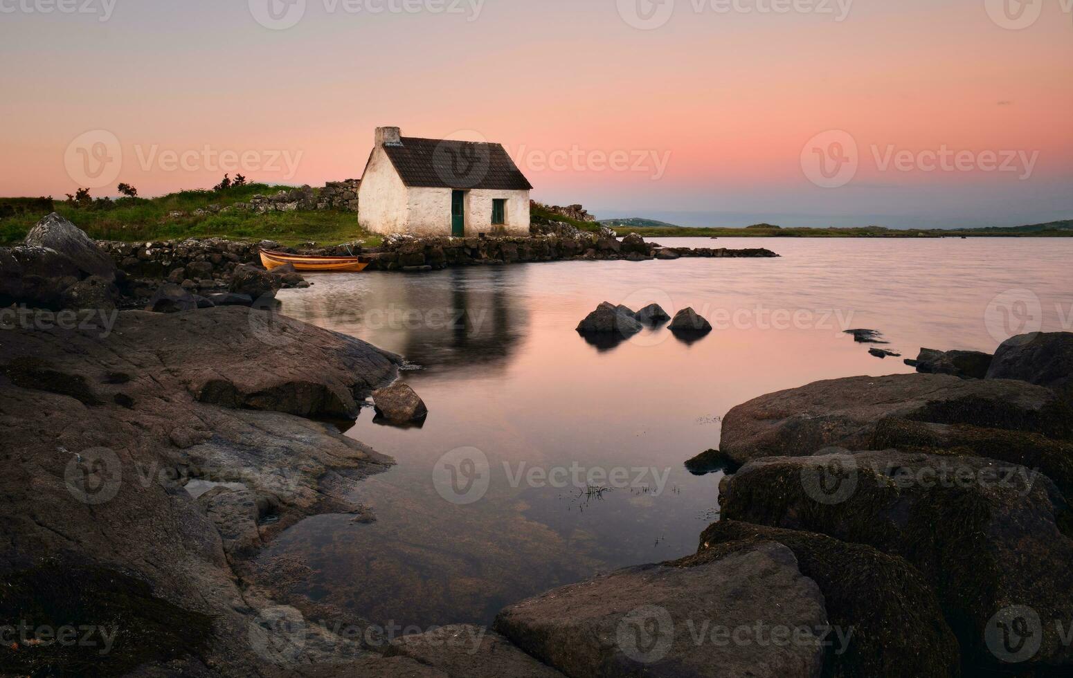Breathtaking sunrise lakeside scenery of fisherman's hut reflected in water at Screebe in Connemara National park ,county Galway ,Ireland photo