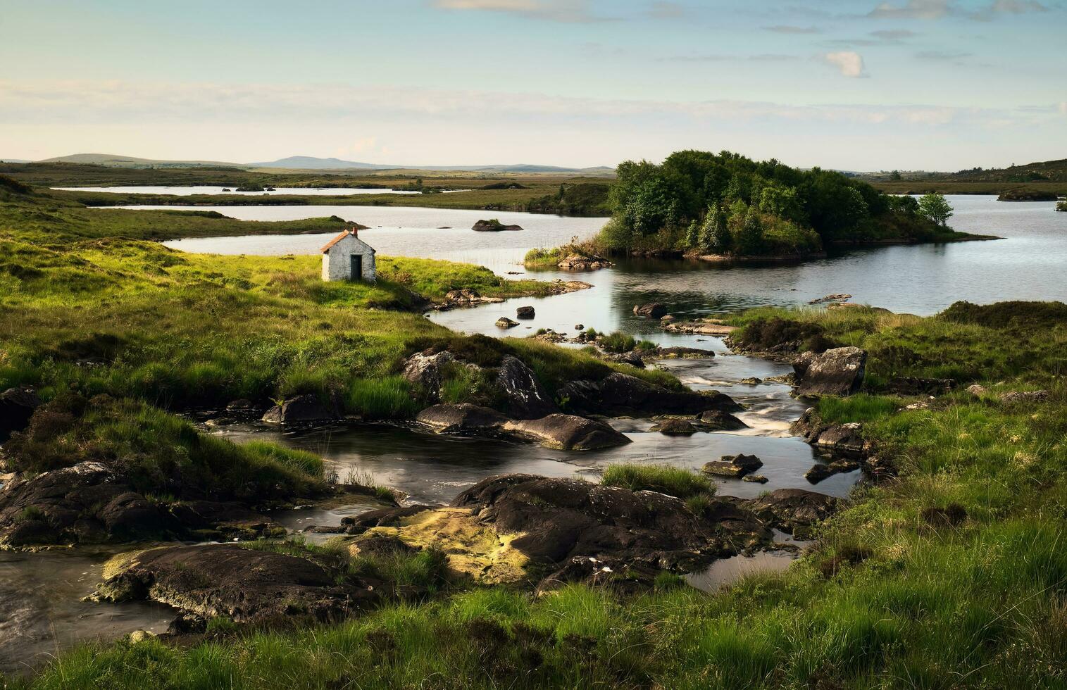 Beautiful landscape scenery of Gillie's hut on green meadow by the river at Connemara National park in County Galway, Ireland photo