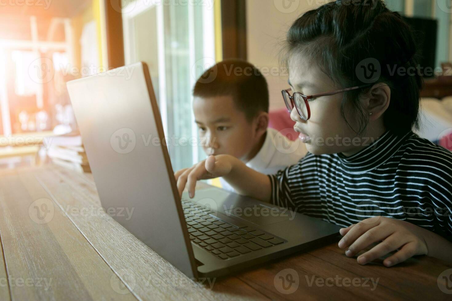 two asian children learning to use computer laptop at home living room photo