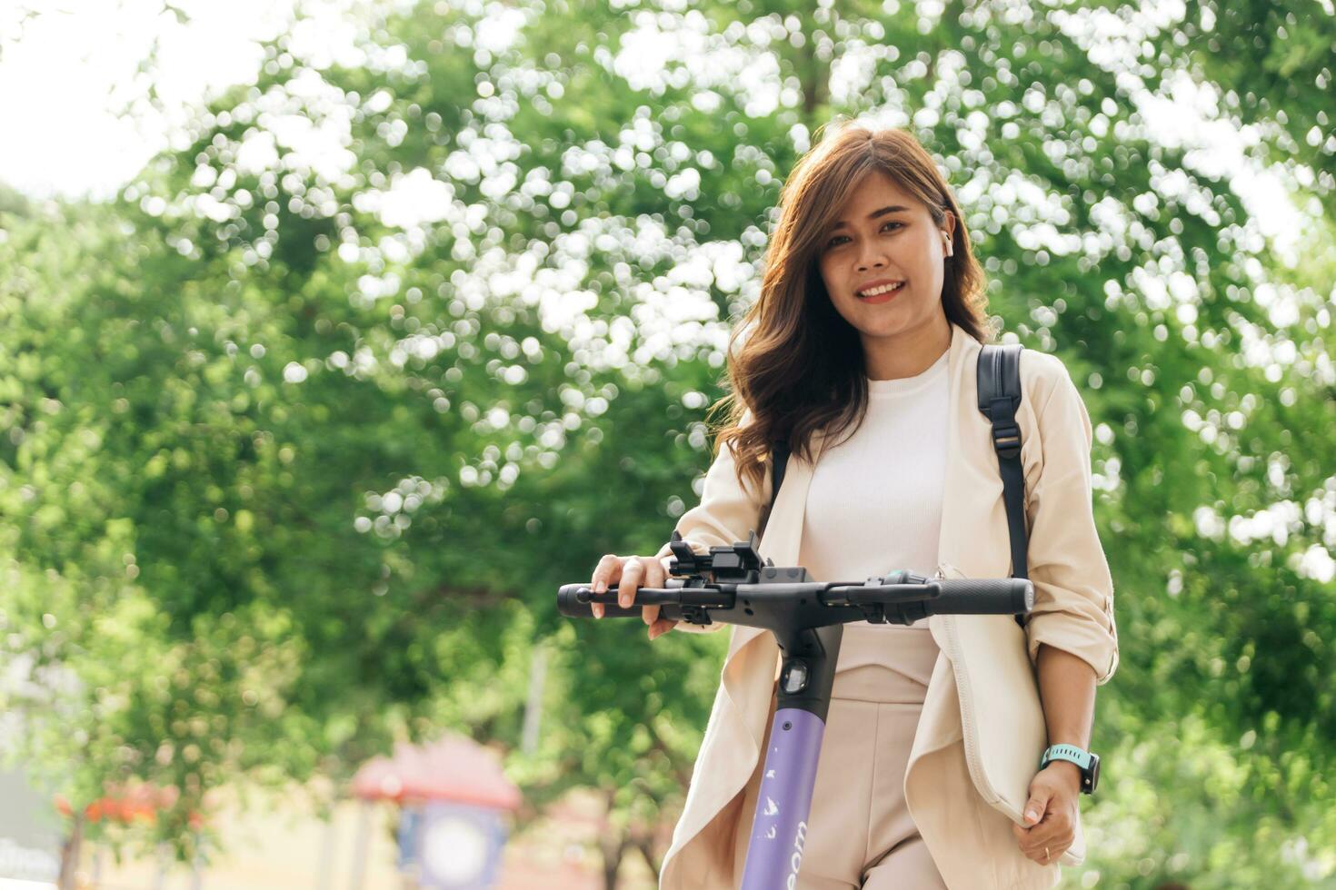 asiático mujer montando eléctrico scooter en el parque, estilo de vida concepto foto