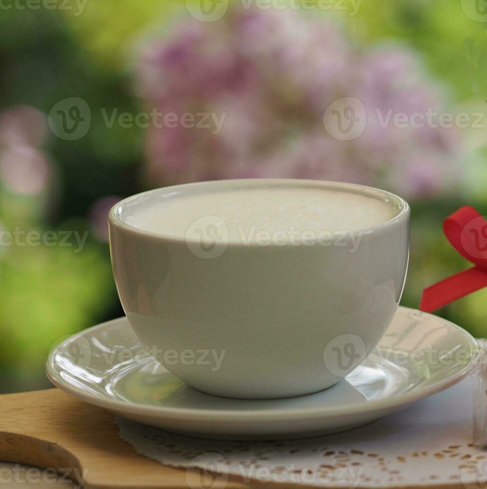 Leche en blanco taza en el mesa borroso de fondo, bebida jarra foto