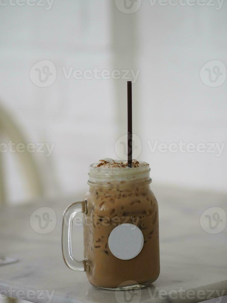 close up view of ice cubes in cold brewed coffee Cappuccino in plastic cup put on bamboo wooden desk blurred background, drink beverage photo