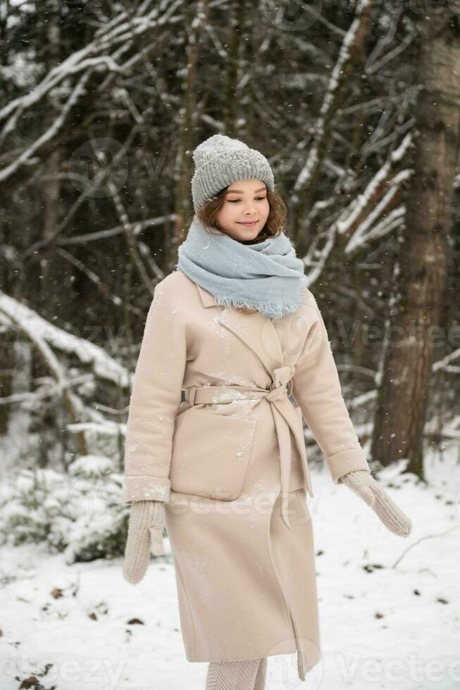 un linda niña camina mediante el bosque en invierno debajo el nieve foto