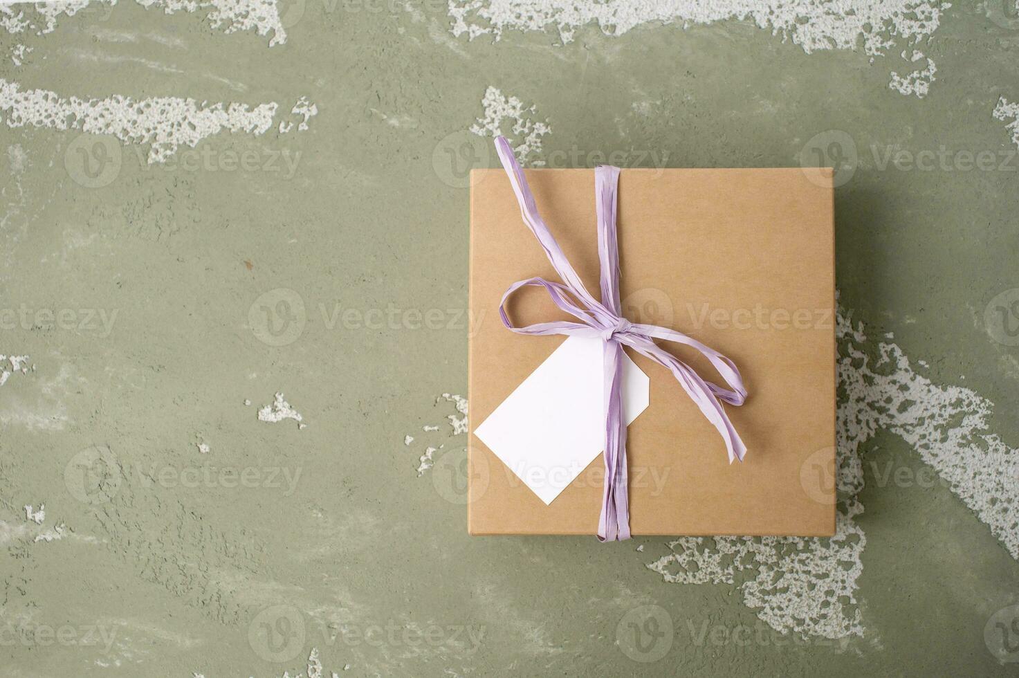 Brown gift square craft box with ribbon, mockup of tag, price tag. Space for text. Color background photo