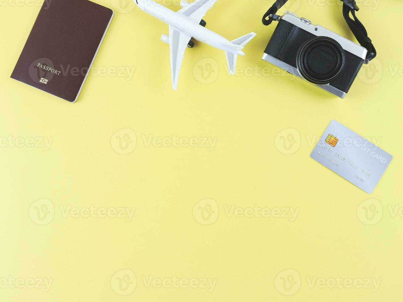 flat lay of airplane model, passport, credit card and digital camera isolated on yellow background with copy space. travel planning concept. photo