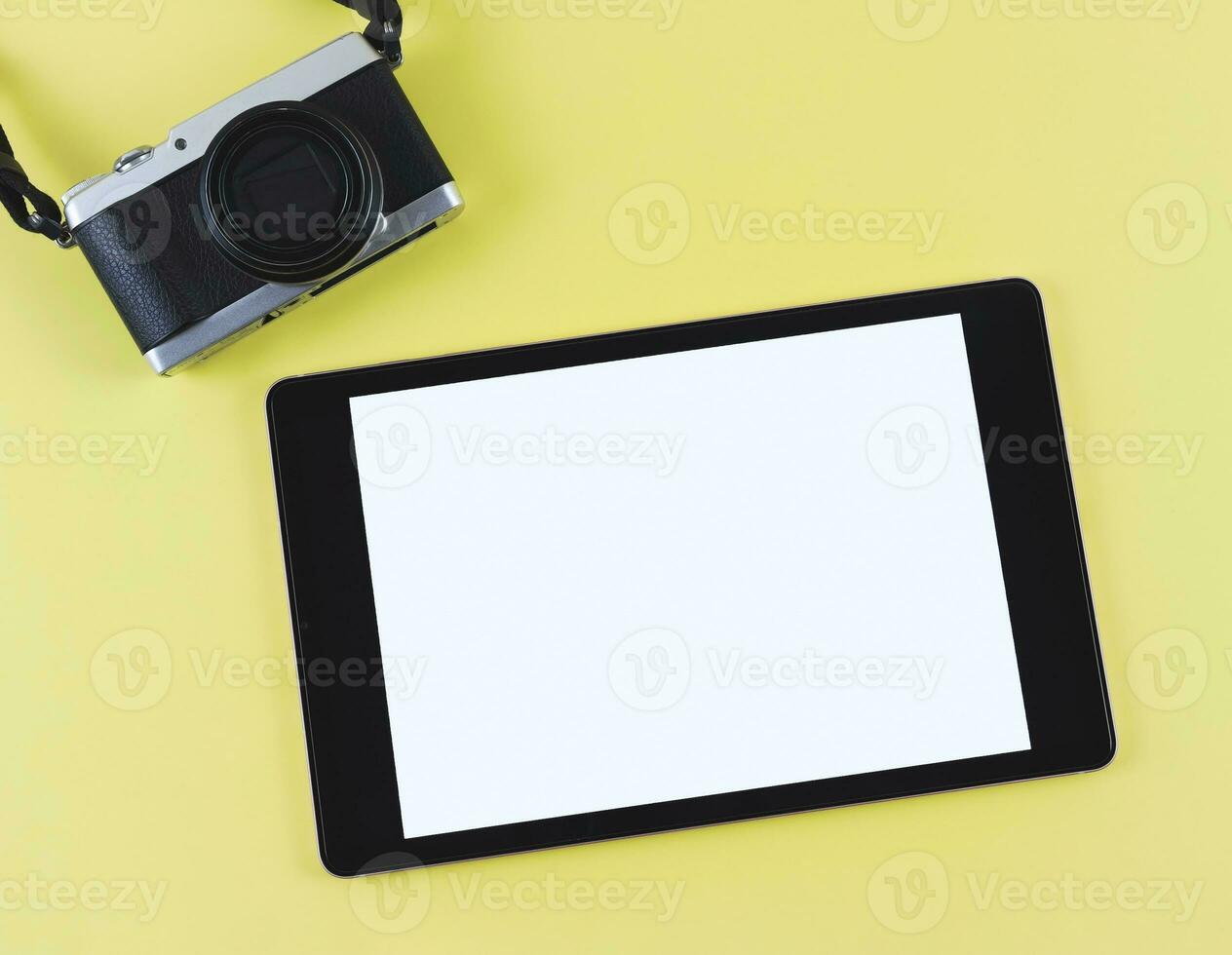 plano laico de digital tableta con blanco blanco pantalla y digital cámara aislado en amarillo antecedentes. foto