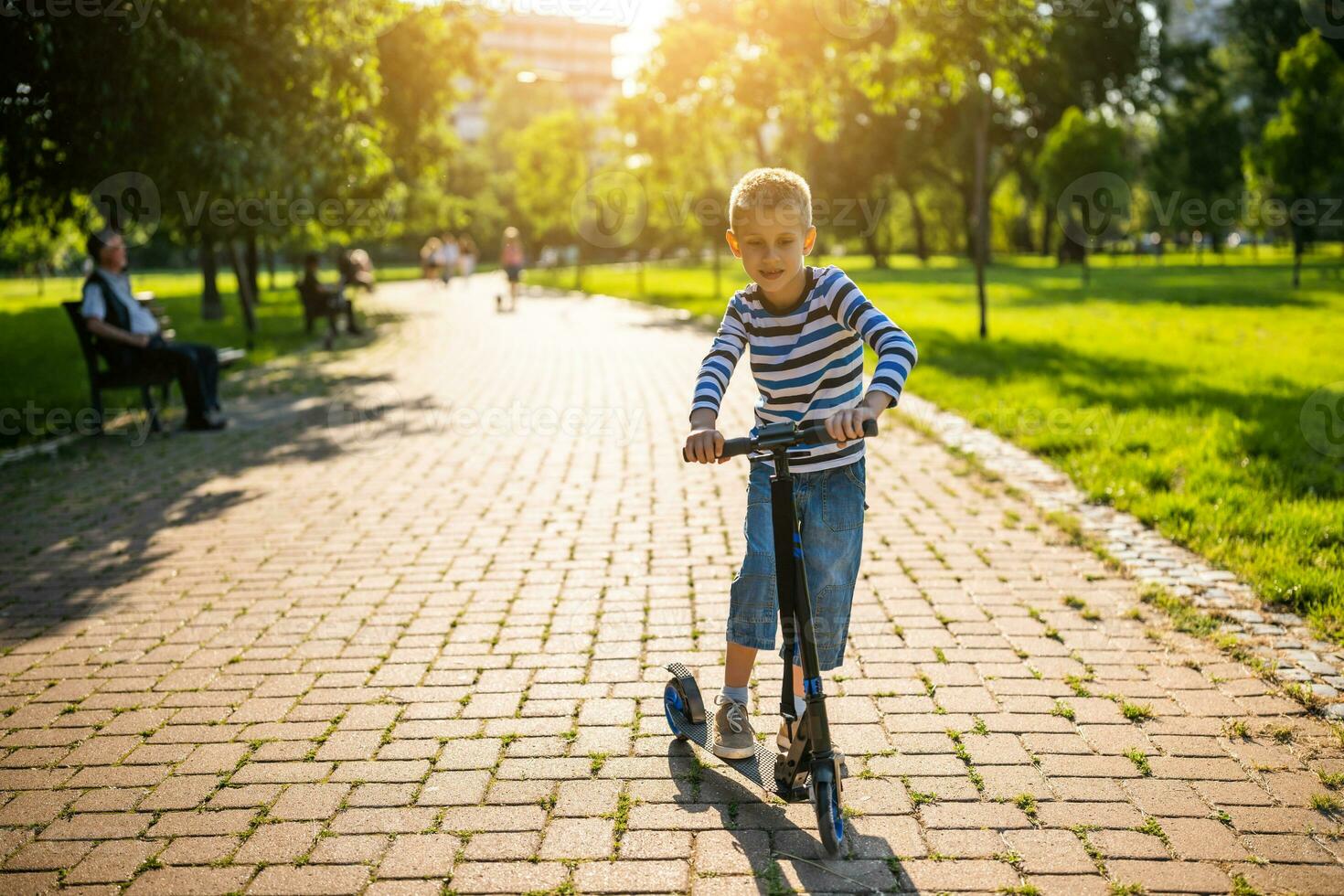 Little boy riding a scooter in the park photo