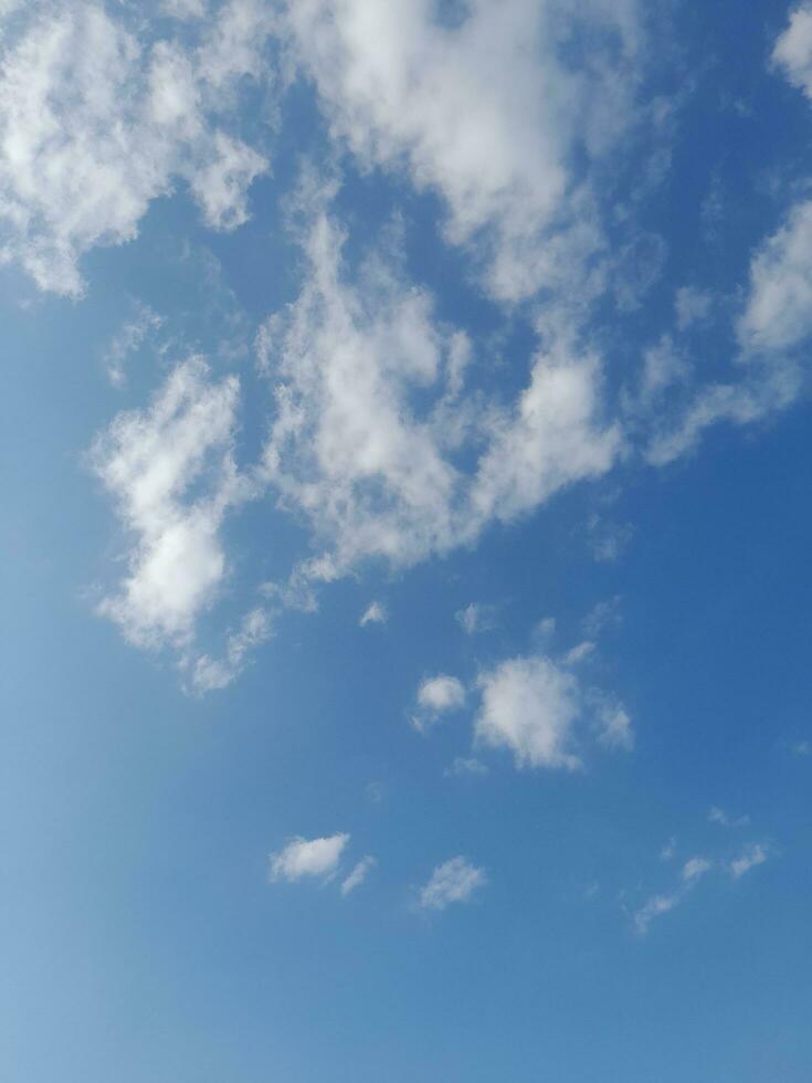 White clouds in the blue sky. Beautiful bright blue background. Light cloudy, good weather. Curly clouds on a sunny day. photo