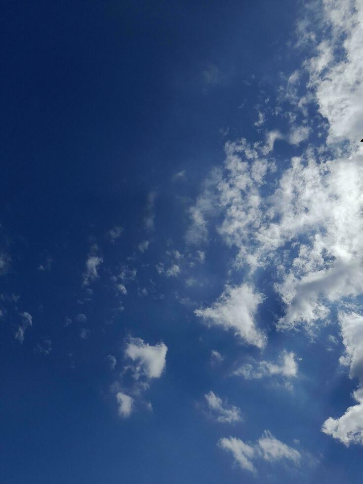 White clouds in the blue sky. Beautiful bright blue background. Light cloudy, good weather. Curly clouds on a sunny day. photo