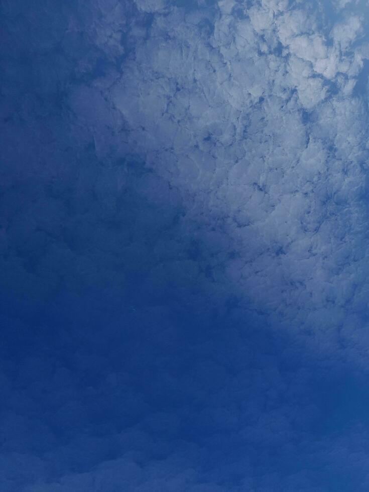 White clouds in the blue sky. Beautiful bright blue background. Light cloudy, good weather. Curly clouds on a sunny day. photo