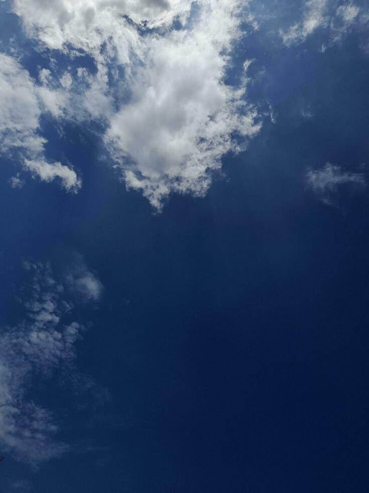 White clouds in the blue sky. Beautiful bright blue background. Light cloudy, good weather. Curly clouds on a sunny day. photo