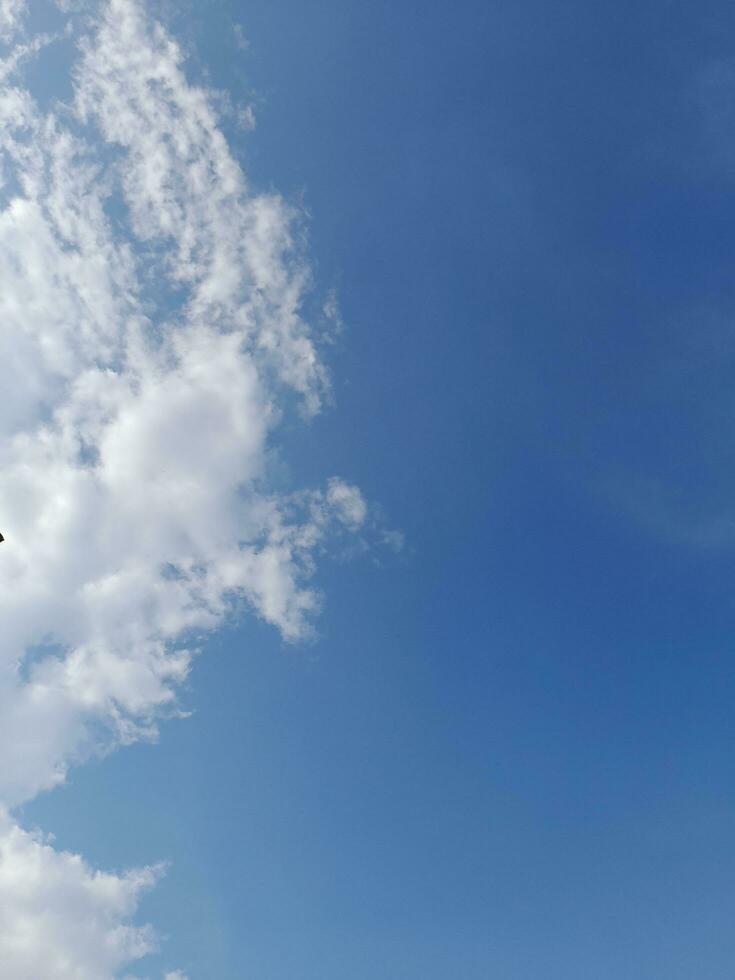 White clouds in the blue sky. Beautiful bright blue background. Light cloudy, good weather. Curly clouds on a sunny day. photo