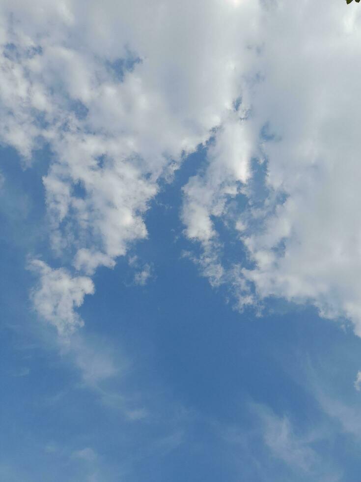 White clouds in the blue sky. Beautiful bright blue background. Light cloudy, good weather. Curly clouds on a sunny day. photo