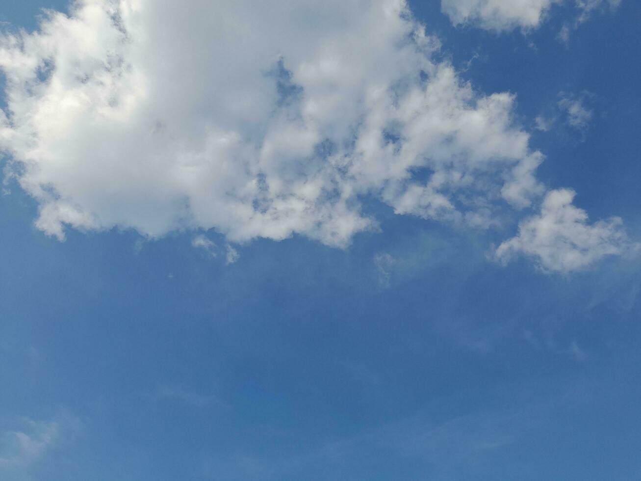 White clouds in the blue sky. Beautiful bright blue background. Light cloudy, good weather. Curly clouds on a sunny day. photo