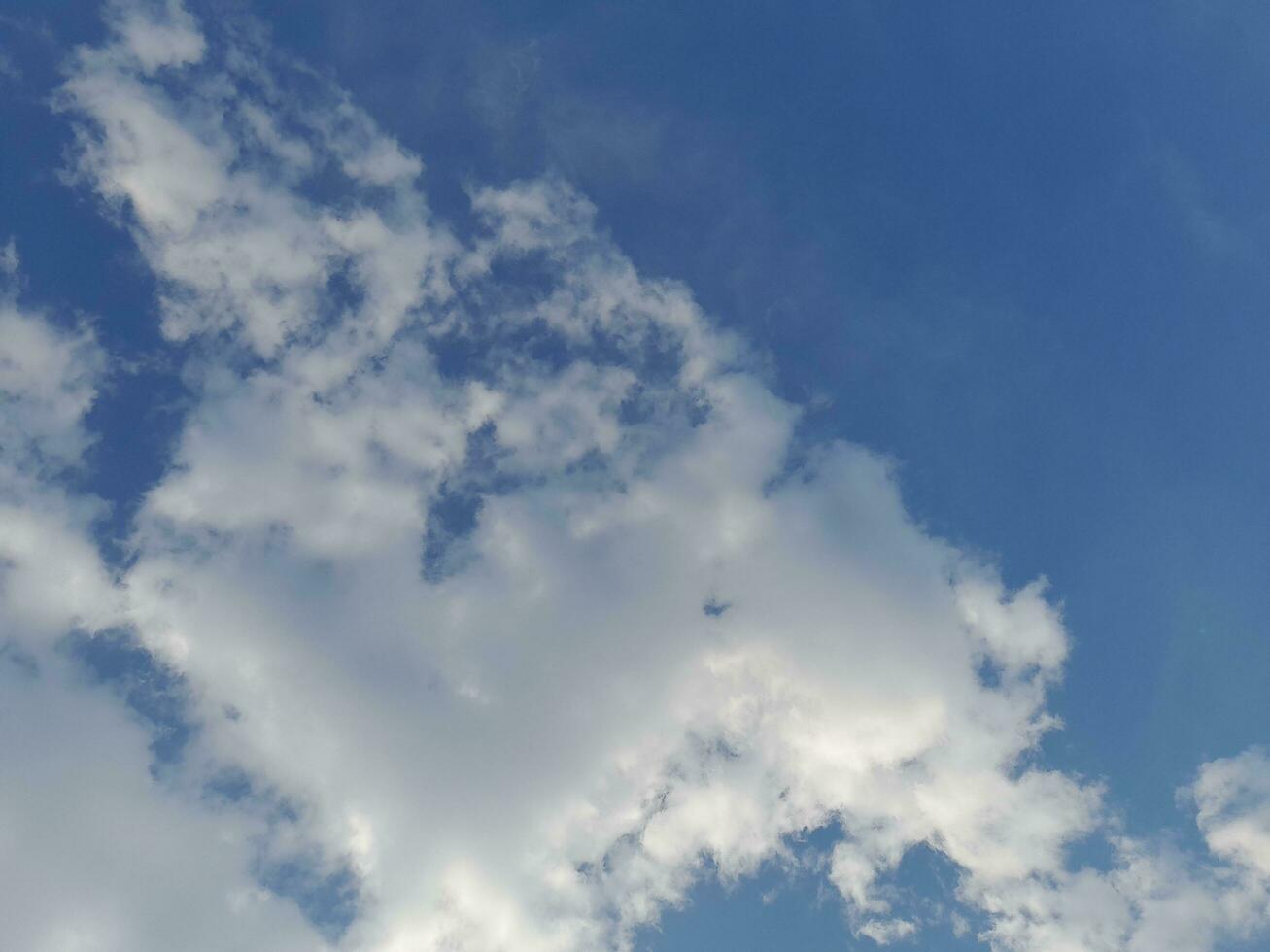 White clouds in the blue sky. Beautiful bright blue background. Light cloudy, good weather. Curly clouds on a sunny day. photo