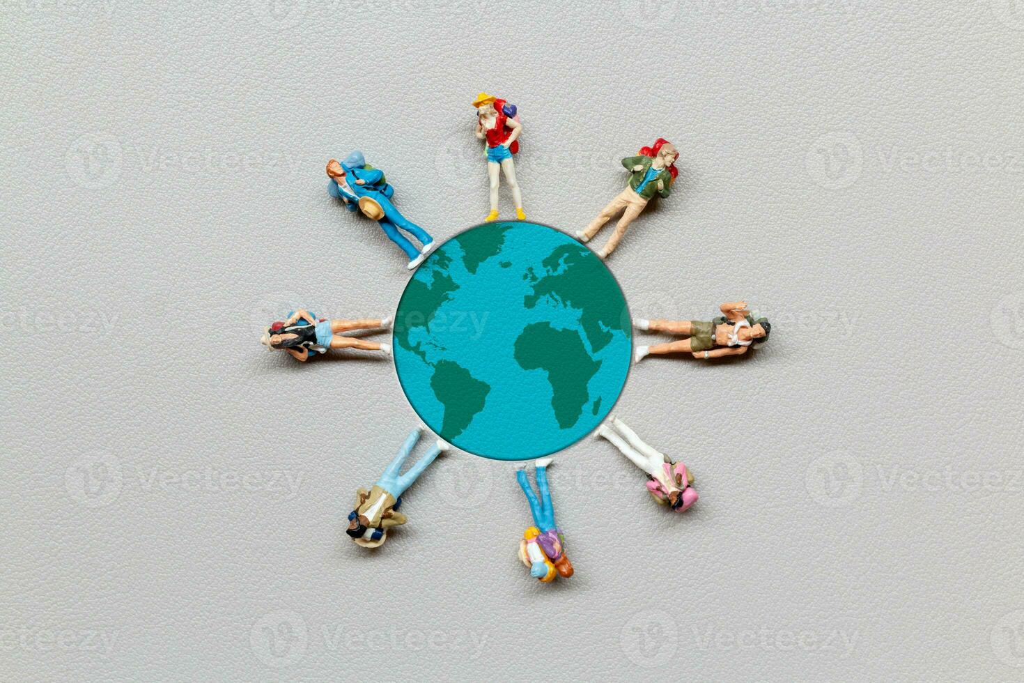 Miniature people standing on the globe with gray background photo