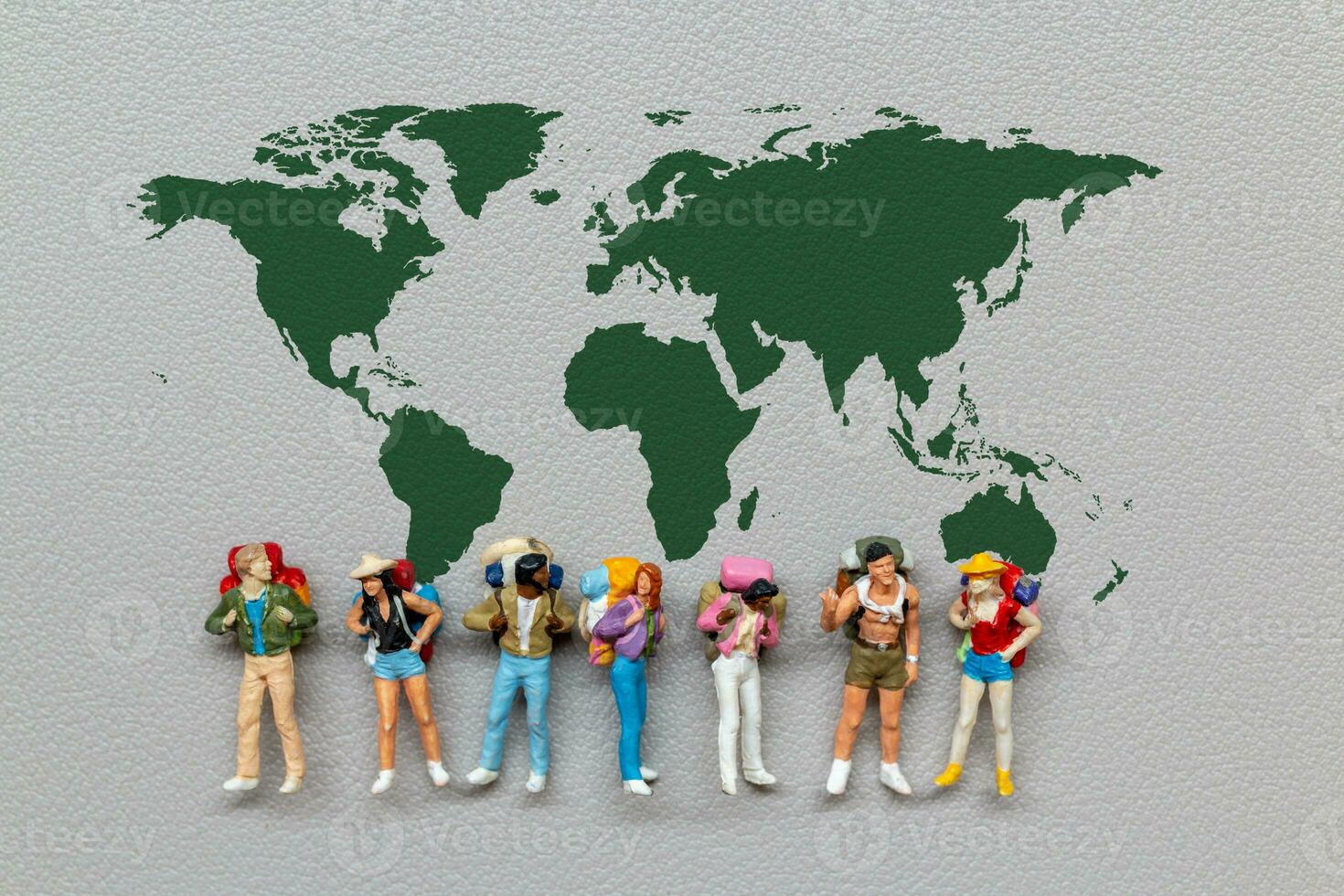 Miniature people standing on the world map with gray background photo