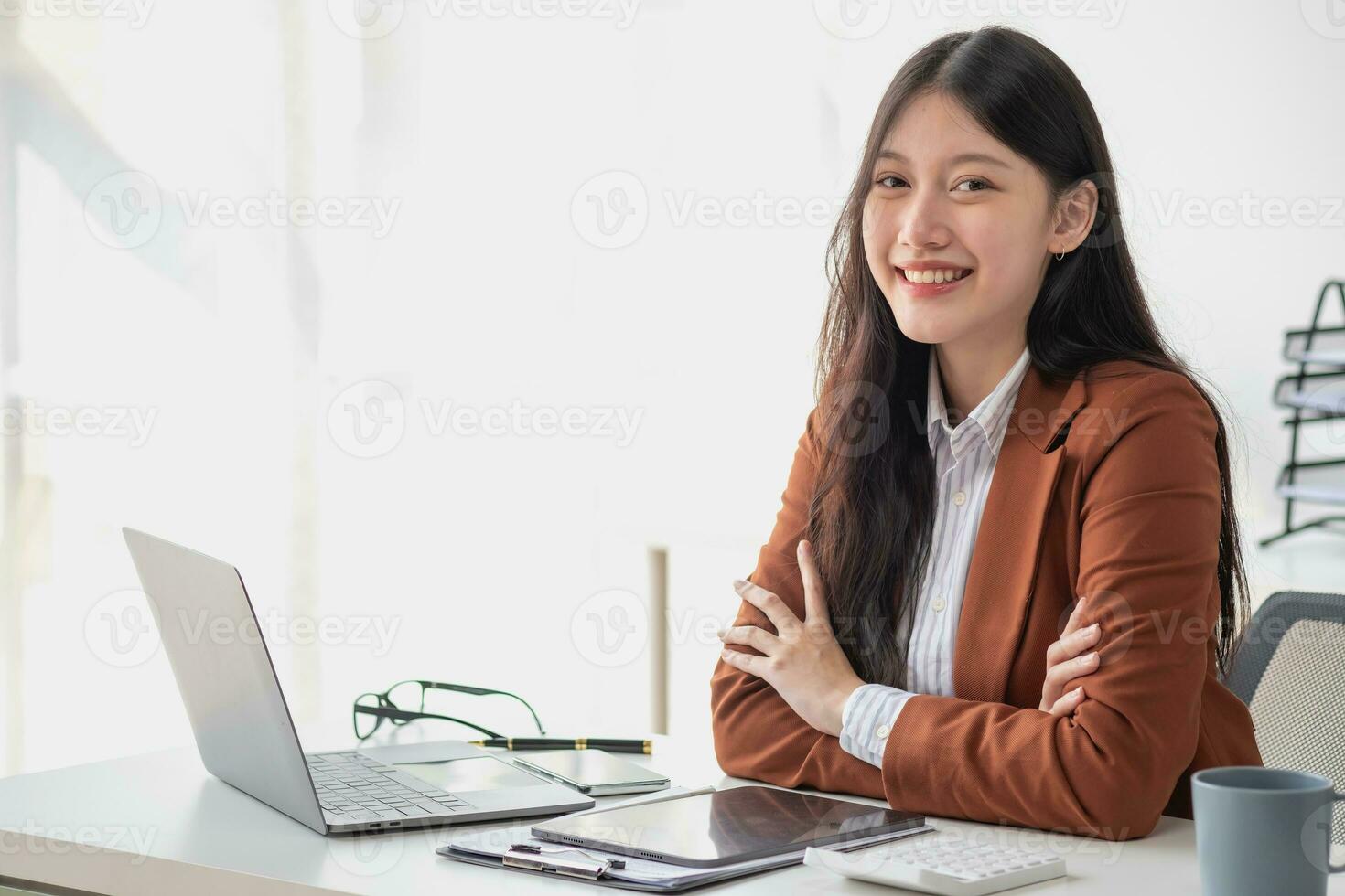 Asian businesswoman smiling confidently successful entrepreneur elegant professional company executive wearing a suit standing in the office with arms crossed. photo
