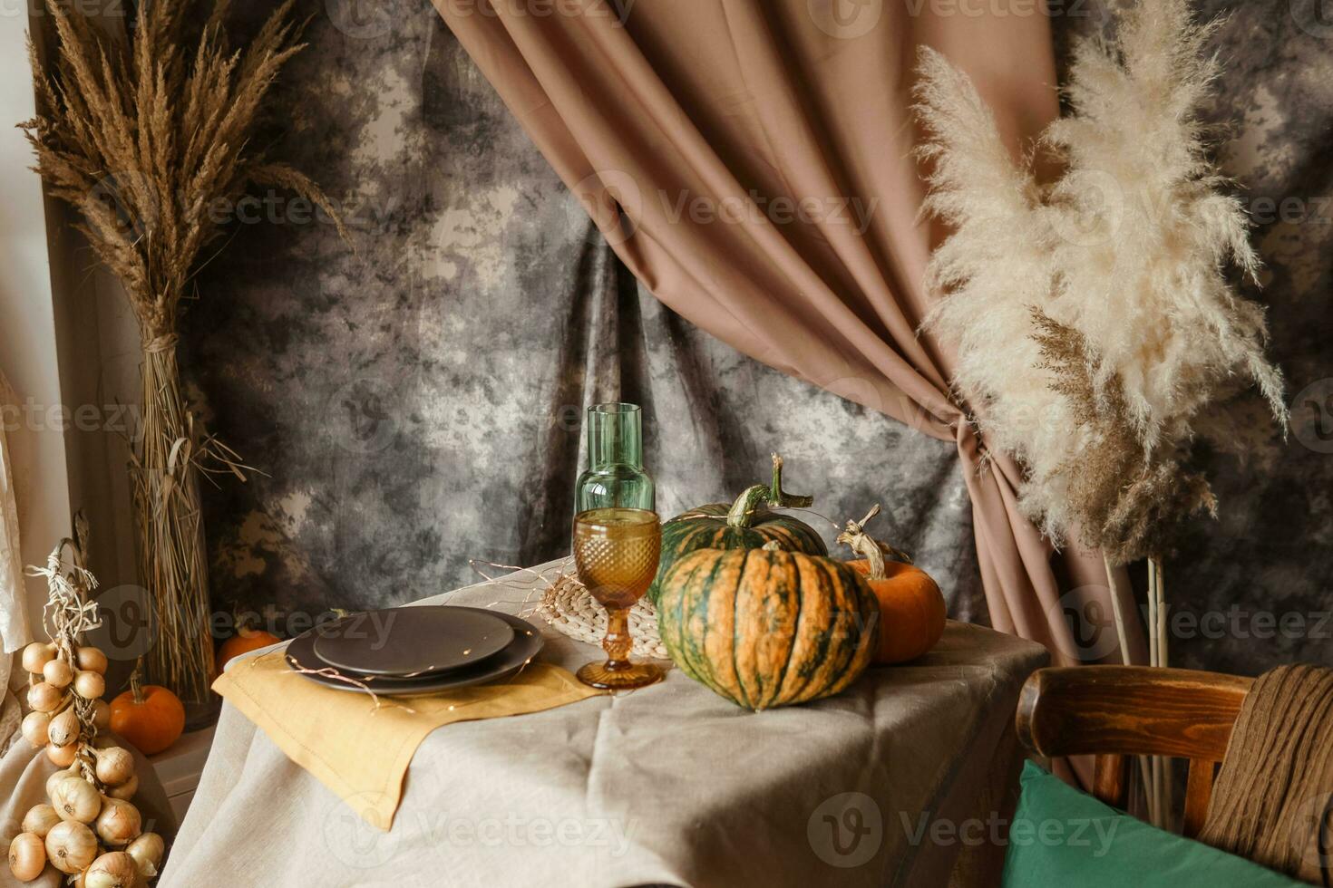 Autumn interior. A table covered with dishes, pumpkins, chair, casual arrangement of Japanese pampas grass. Interior in the photo Studio.
