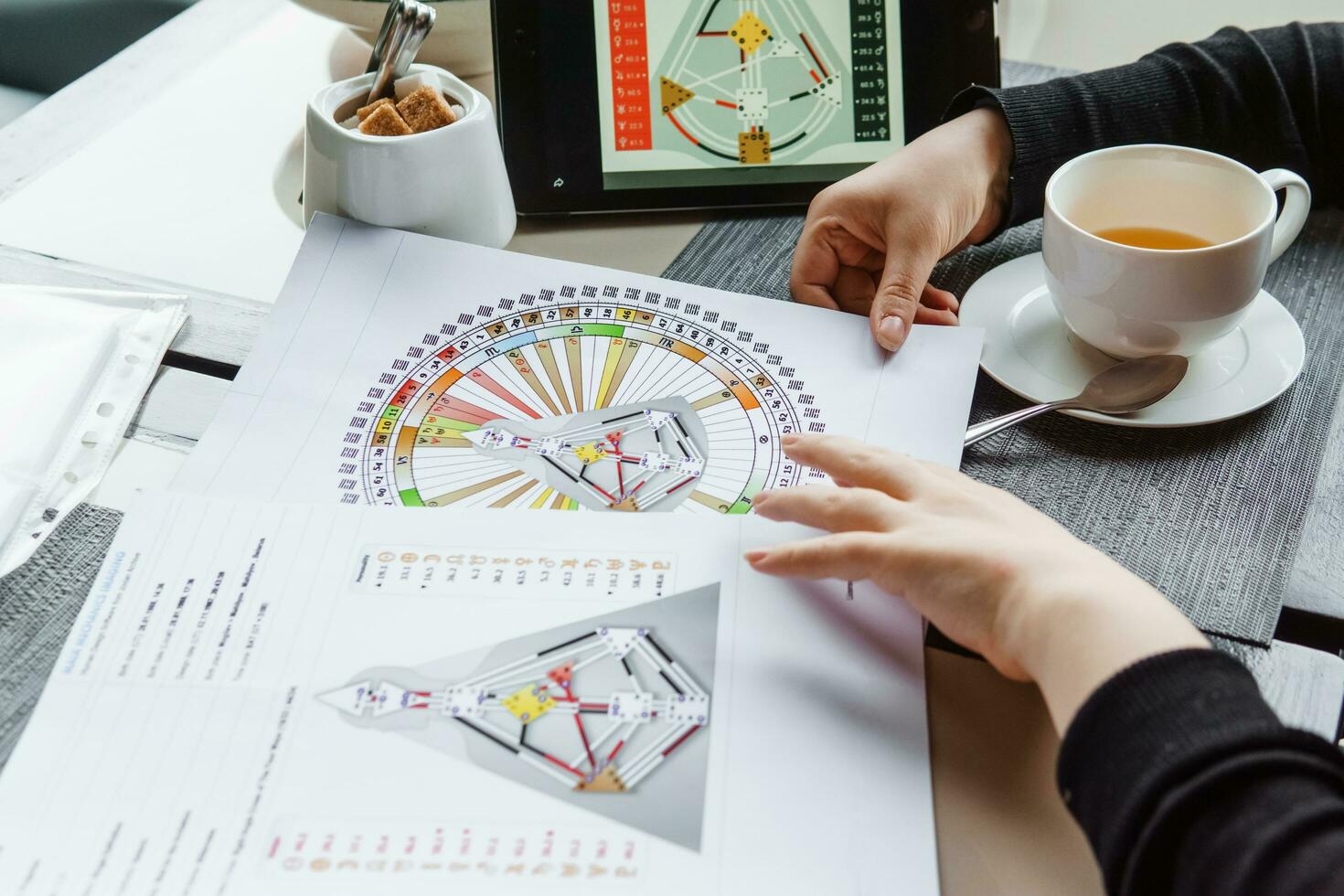 TVER, RUSSIA - FEBRUARY 12, 2023 A woman at the table is studying a rave mandala by human design. Rave mandala on the table close-up. The concept of esoteric teachings. photo
