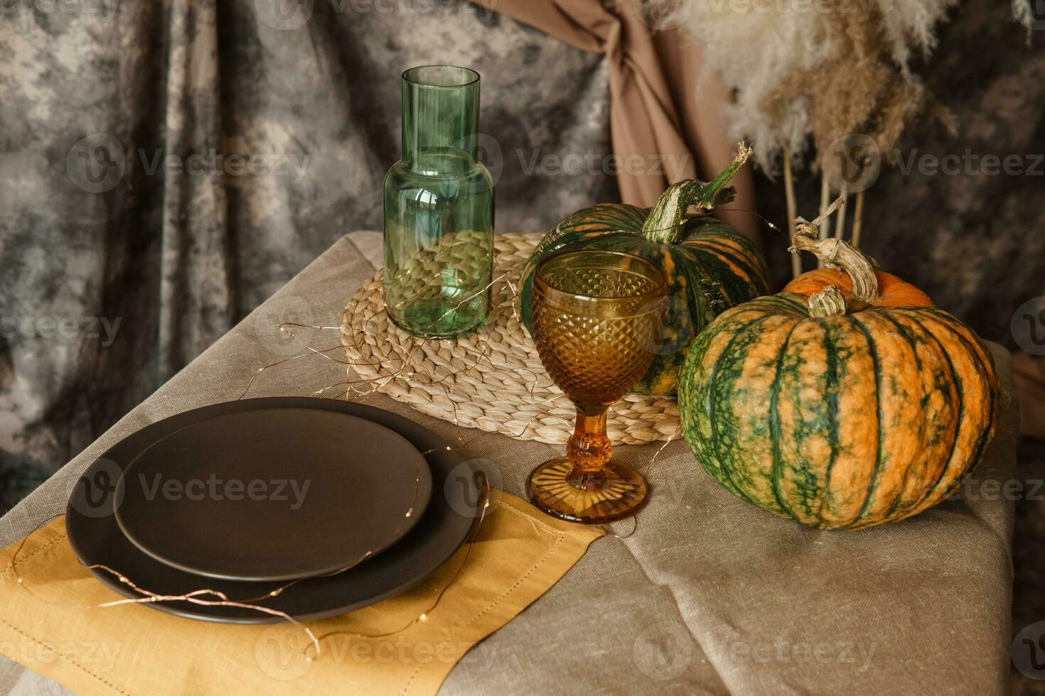 Autumn interior. A table covered with dishes, pumpkins, a relaxed composition of Japanese pampas grass. Interior in the photo Studio. Close - up of a decorated autumn table.
