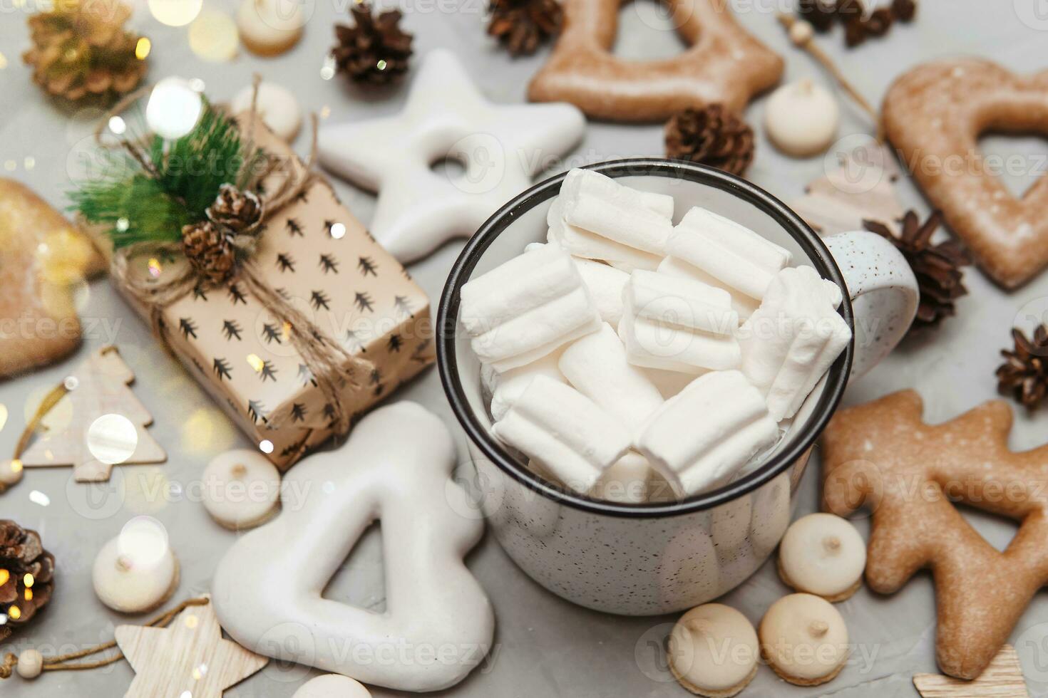 A cup of cocoa with marshmallows and New Year's gingerbread and a gift on the table, bokeh lights in the foreground. The concept of desserts and drinks during the Christmas holidays. photo