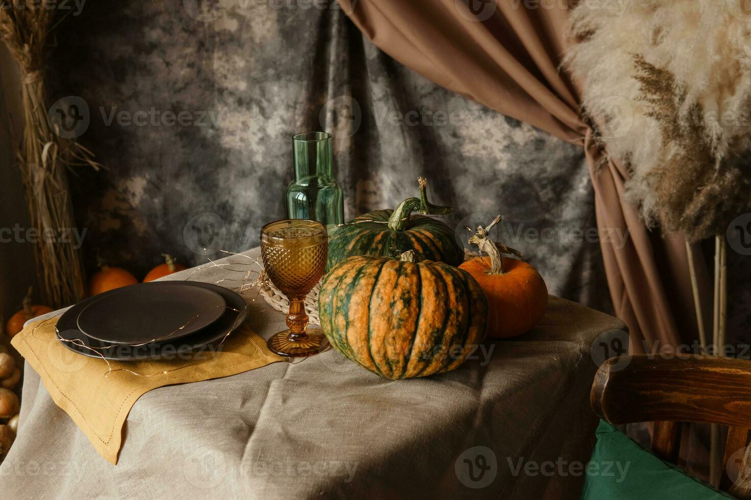 Autumn interior. A table covered with dishes, pumpkins, chair, casual arrangement of Japanese pampas grass. Interior in the photo Studio.