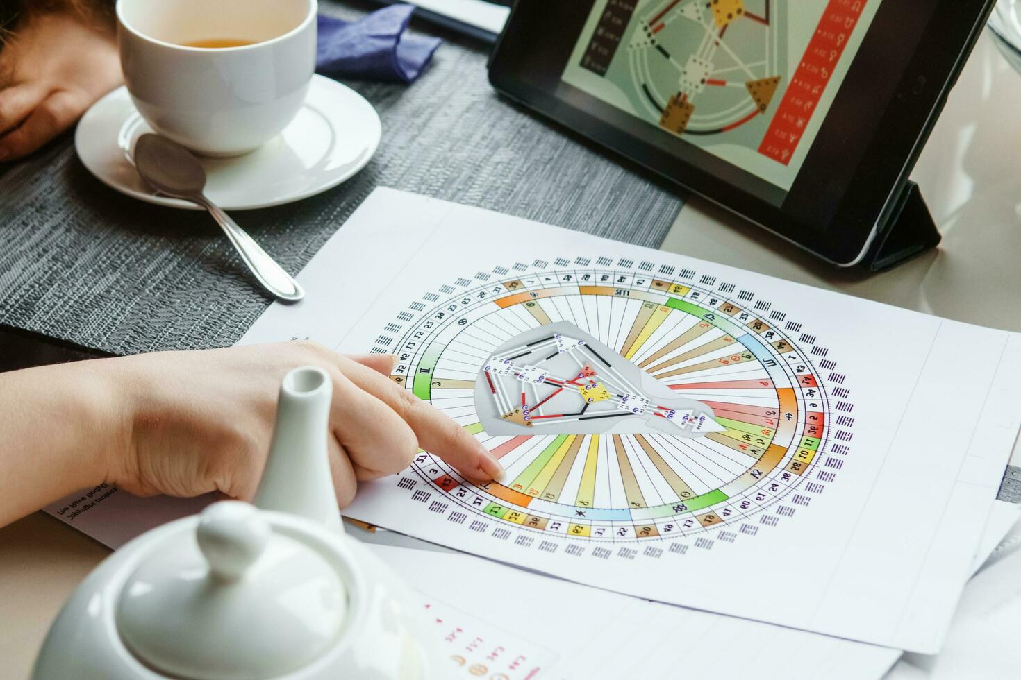 TVER, RUSSIA - FEBRUARY 12, 2023 A woman at the table is studying a rave mandala by human design. Rave mandala on the table close-up. The concept of esoteric teachings. photo