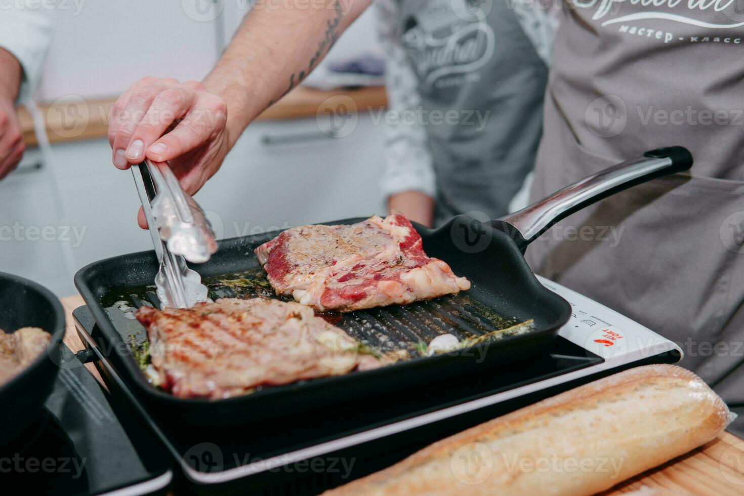 cooking steaks in a pan. cooking beef at the culinary master class. the hands of the chef in black gloves. photo