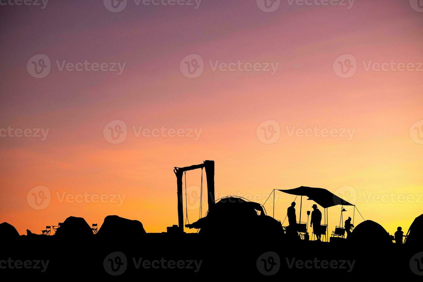 Silhouette of camping tent of tourists on blurred twilight light orange background, photo