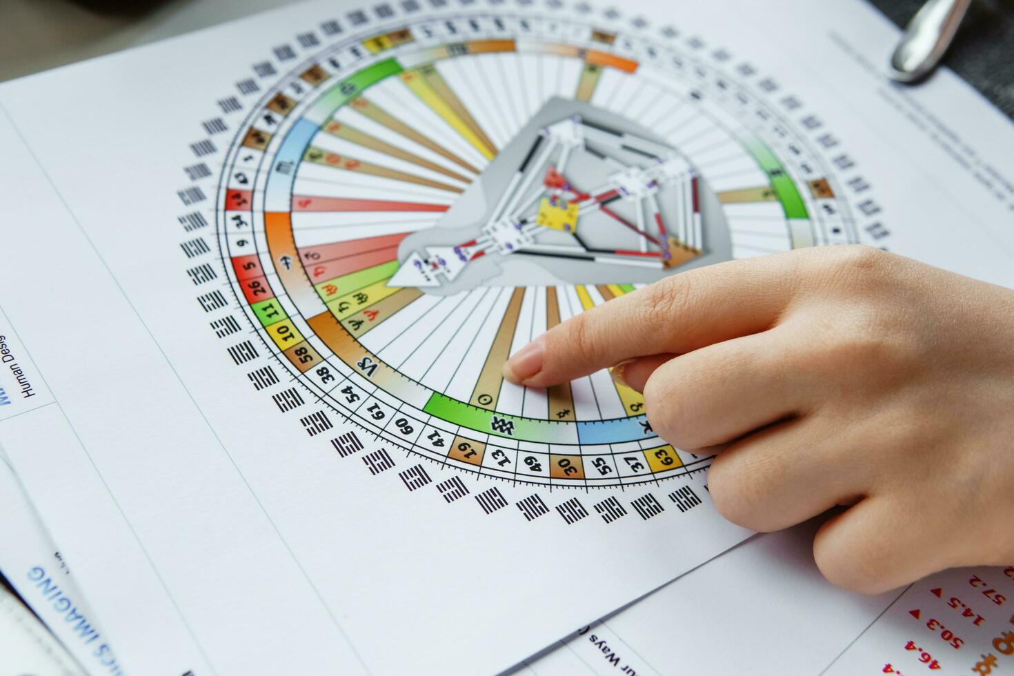 TVER, RUSSIA - FEBRUARY 12, 2023 A woman at the table is studying a rave mandala by human design. Rave mandala on the table close-up. The concept of esoteric teachings. photo