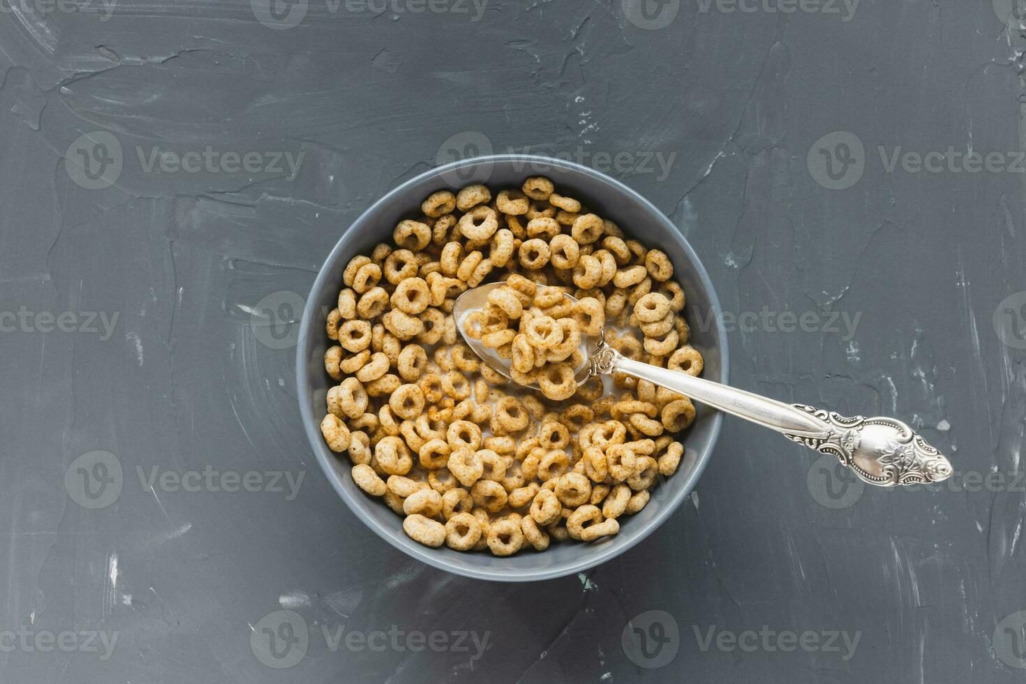 Delicious honey cheerios cereal in bowl with milk and spoon, copy space photo
