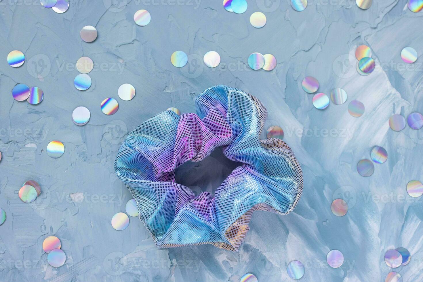 Trendy holographic scrunchie and confetti on blue photo