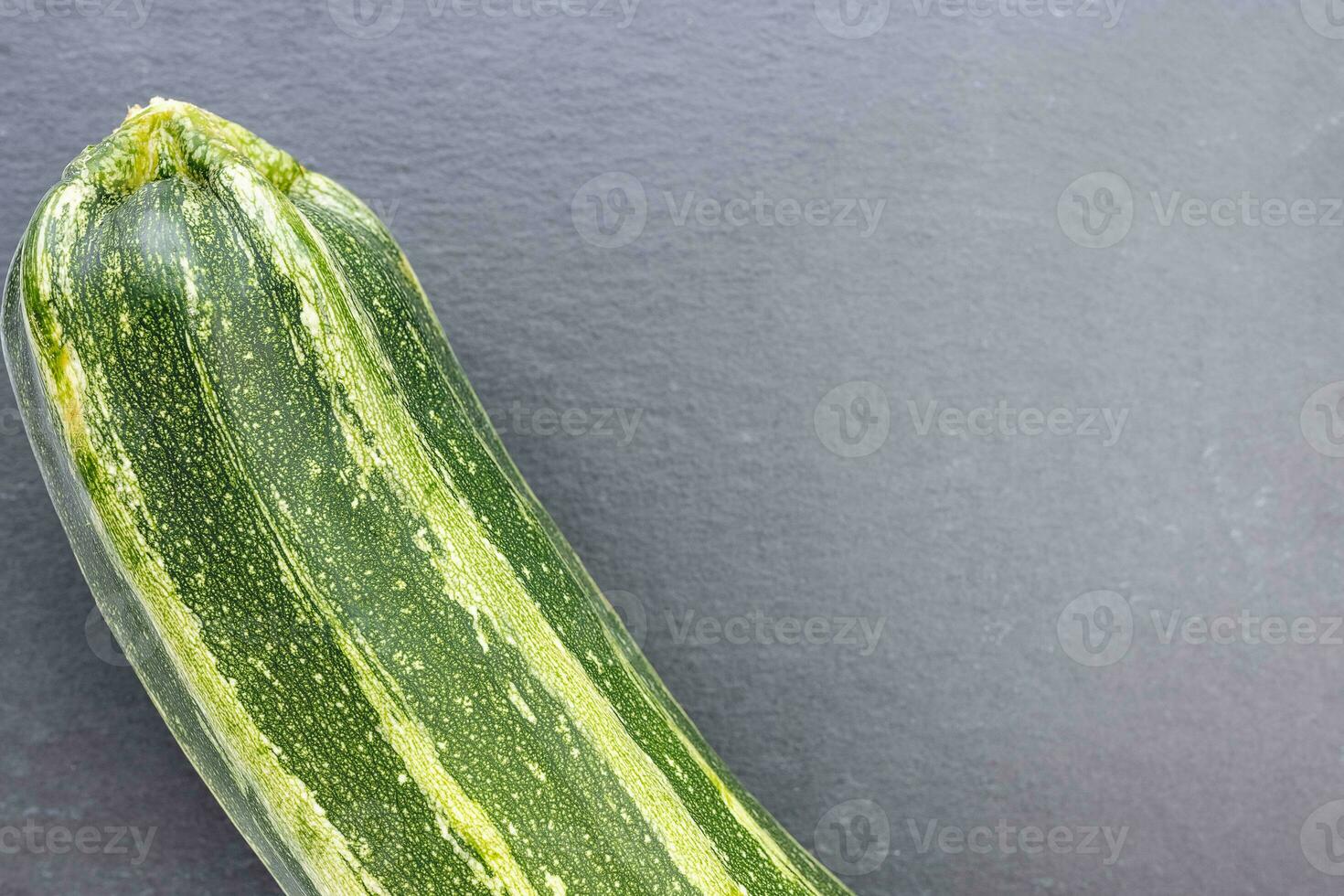 Fresh green striped zucchini on a gray background photo