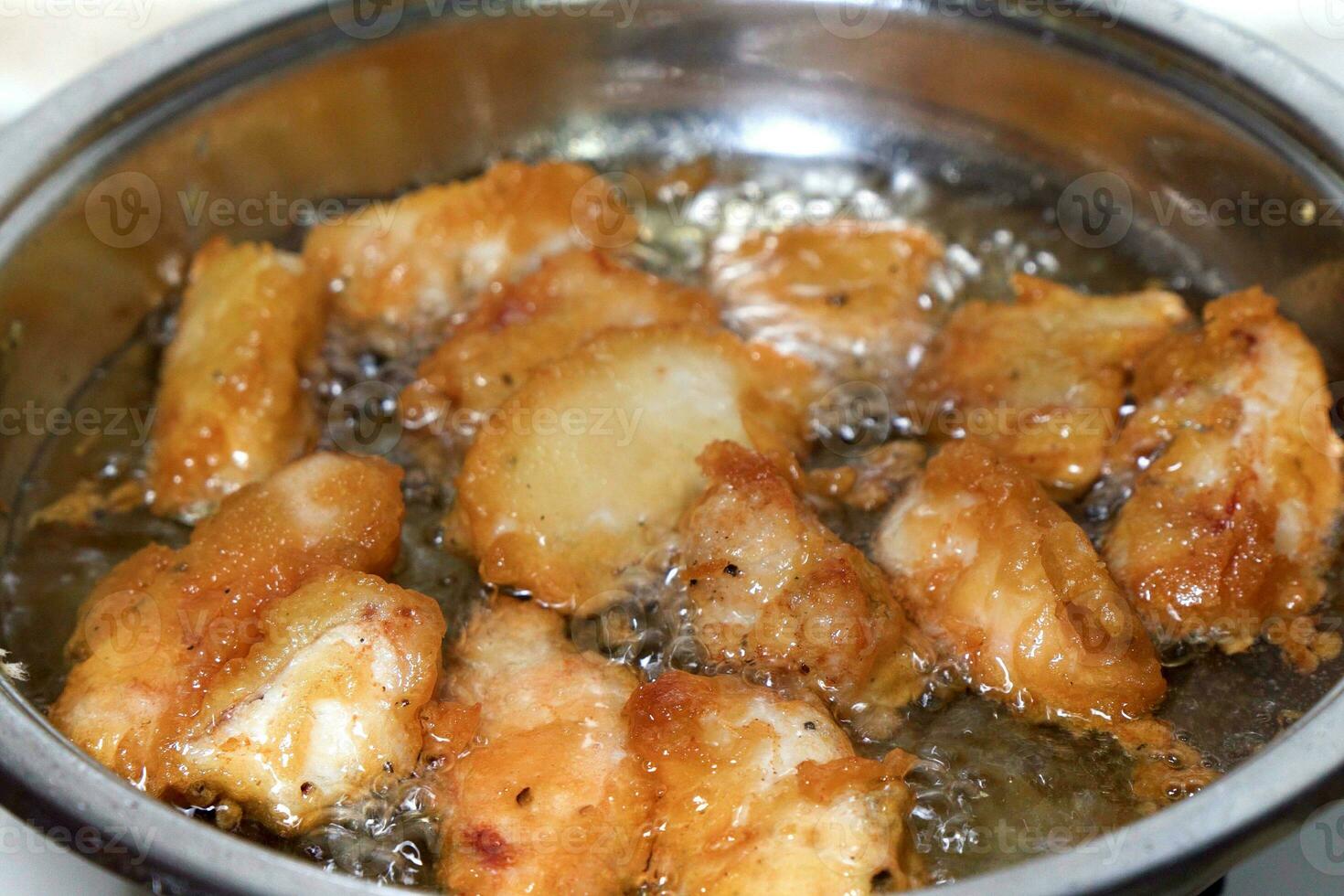 Pieces of fish in batter are fried in boiling oil. photo