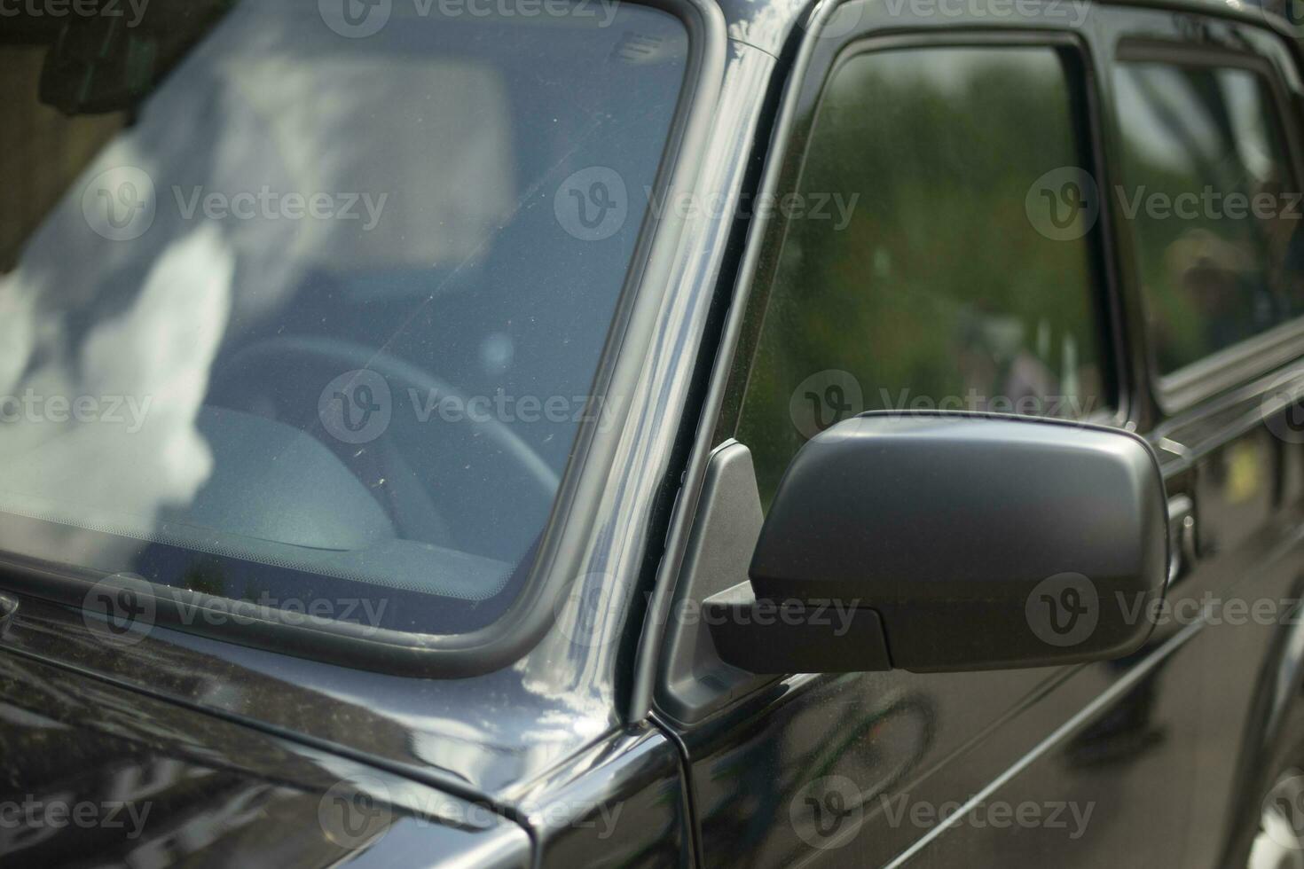 Black car in detail. Front rearview mirror. Car windshield. photo