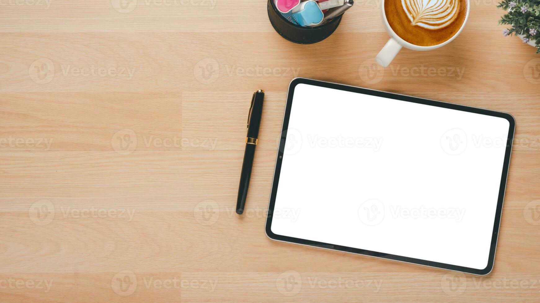 Wooden desk workplace with blank screen tablet, pen and cup of coffee, Top view flat lay with copy space. photo