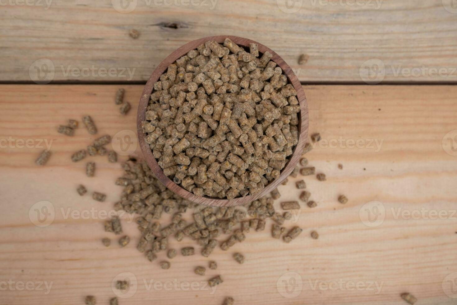 selectivo atención en marrón pollo pellets en un de madera bol, pellets son pollo alimentar hecho desde maíz y vegetales mezclado con agua foto