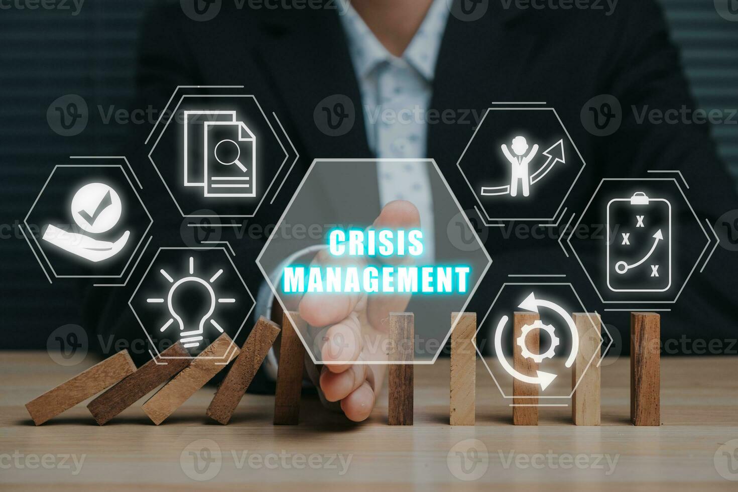 Crisis management concept,  Business person stopping falling dominos with his hand on desk with crisis management icon on virtual screen. photo