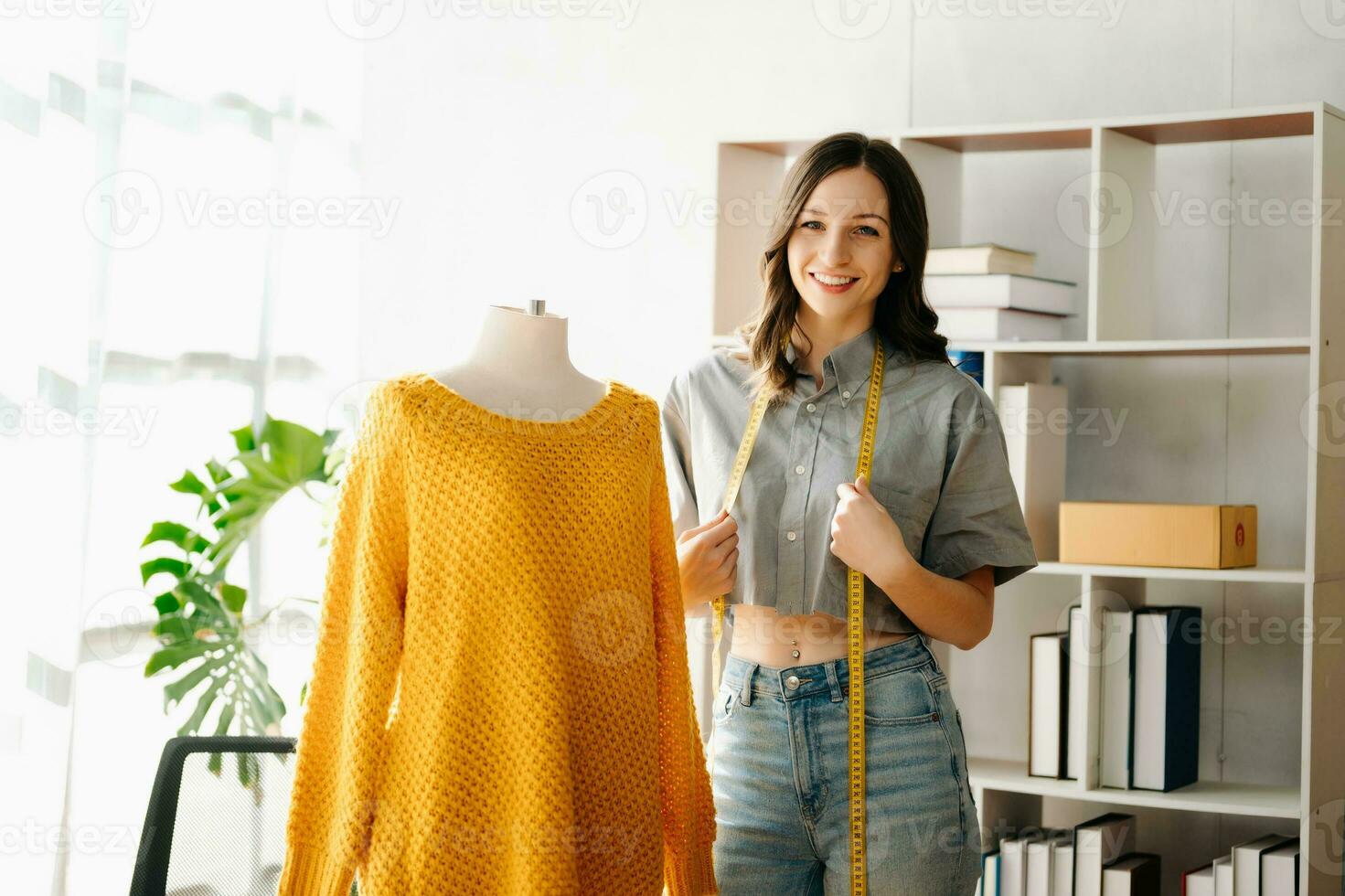 Caucasian young woman on desk in home office of fashion designer and holds tablet, laptop and smartphone. photo
