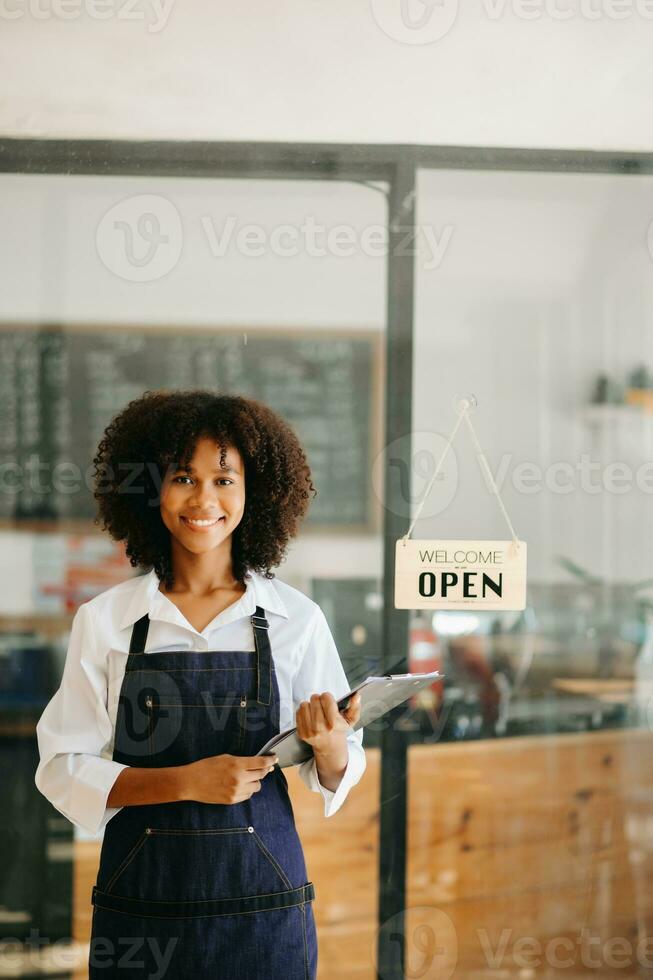 Startup successful small business owner sme African woman stand with tablet  in cafe restaurant. woman barista cafe owner. photo