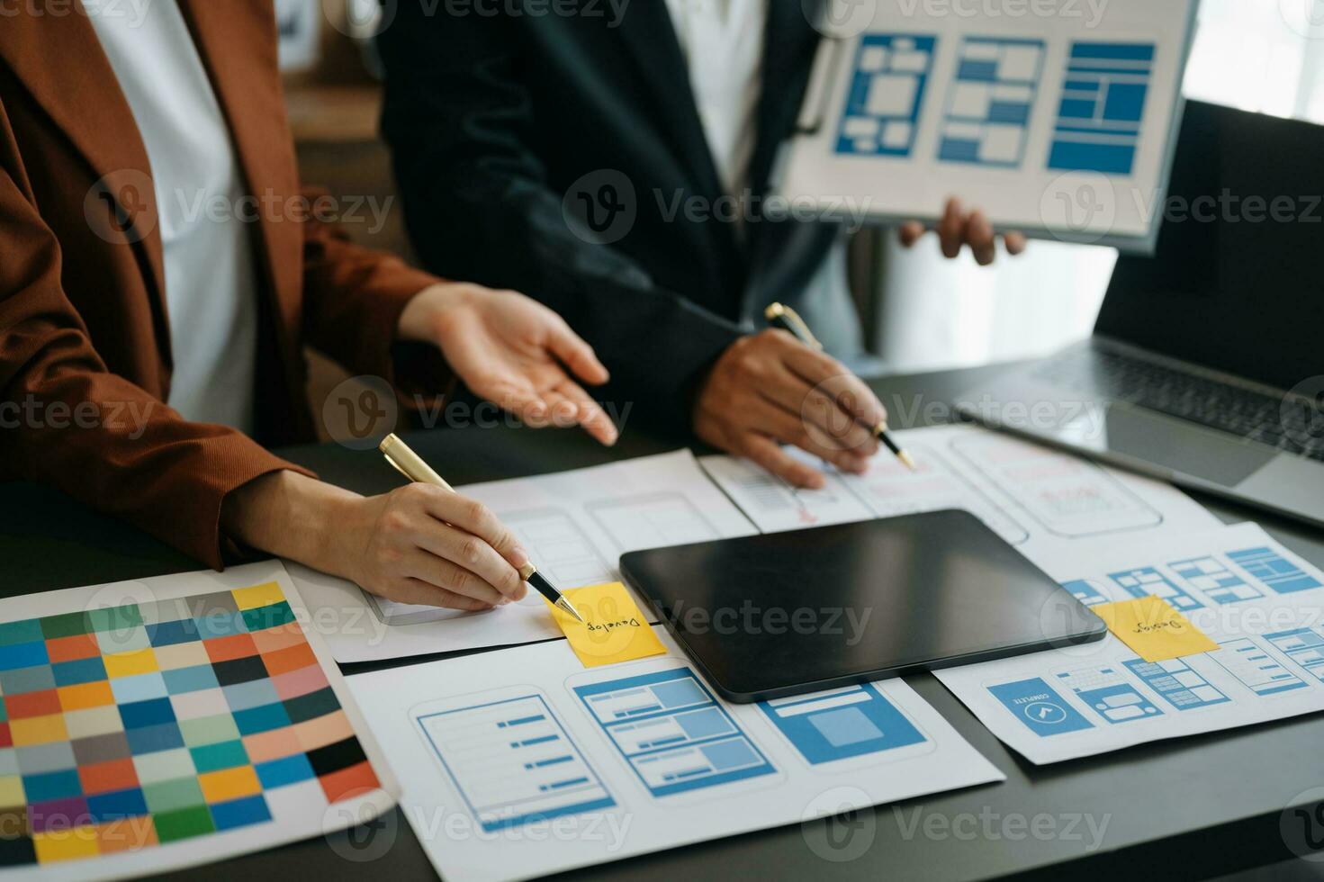 UX developer and ui designer brainstorming about mobile app interface wireframe design with customer breif and color code at office. photo