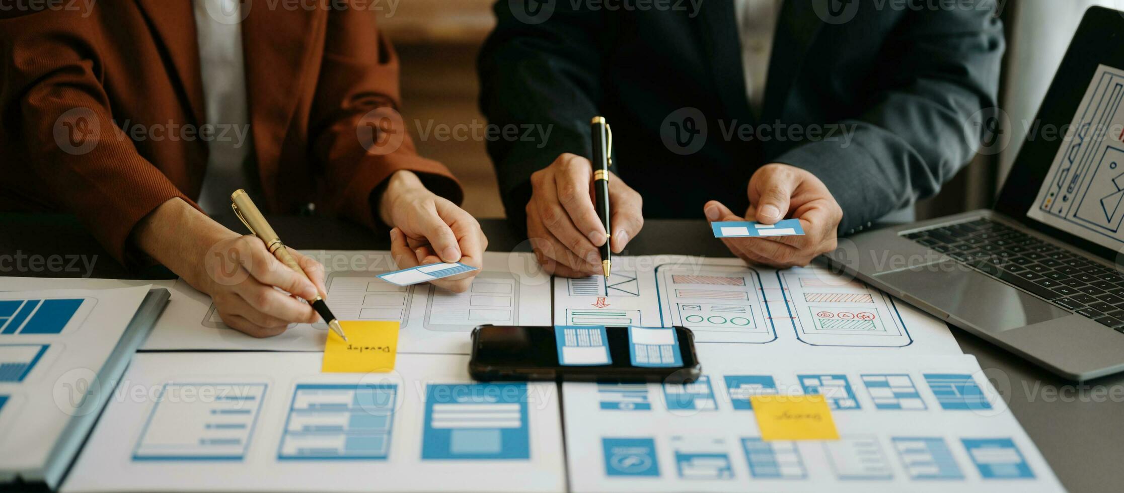 El desarrollador de ux y el diseñador de ui hacen una lluvia de ideas sobre el diseño de la estructura alámbrica de la interfaz de la aplicación móvil con el resumen del cliente y el código de color en la oficina. foto