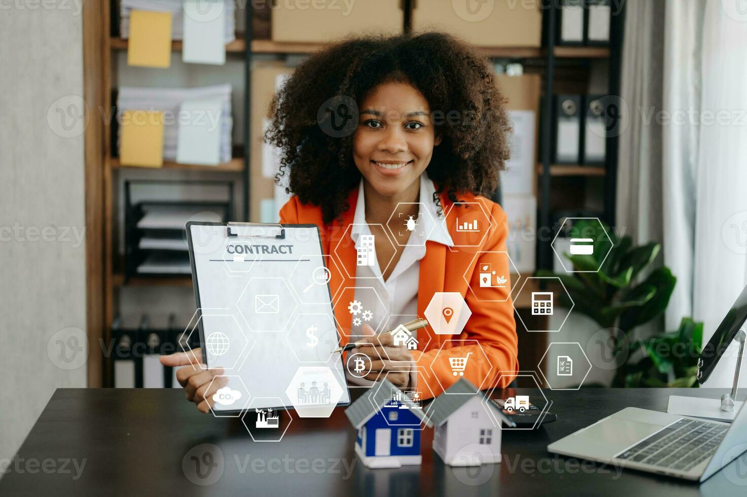 Young real estate agent worker working with laptop and tablet at table in office and small house beside it. photo