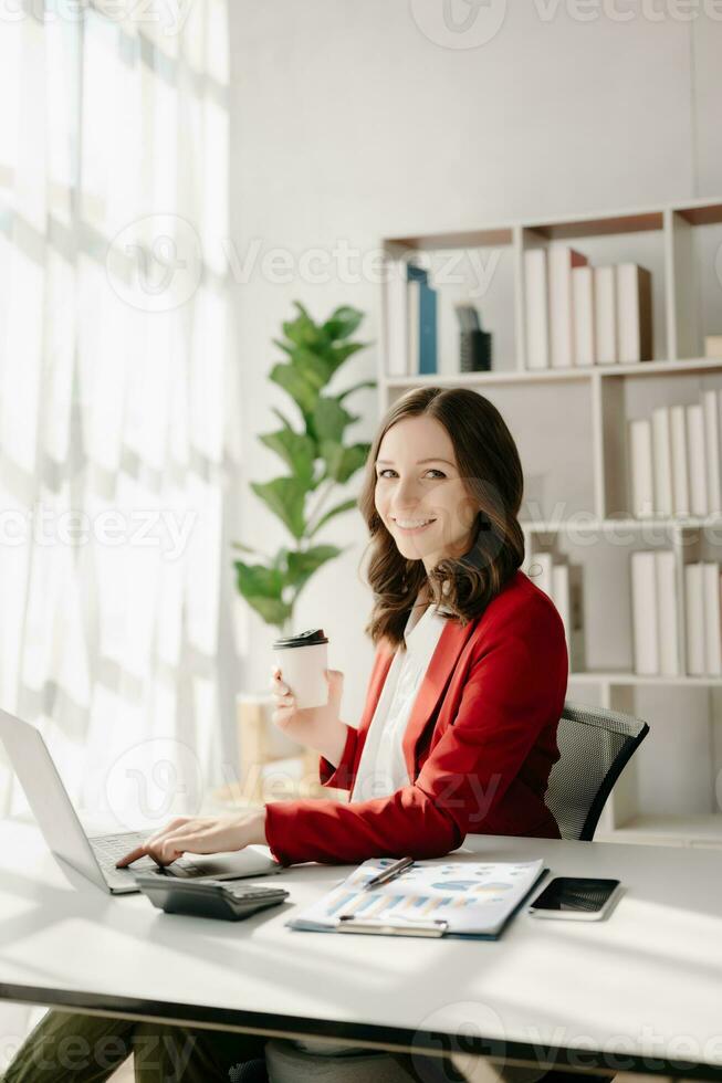 Confident Asian woman with a smile standing holding notepad and tablet at the modern office. photo