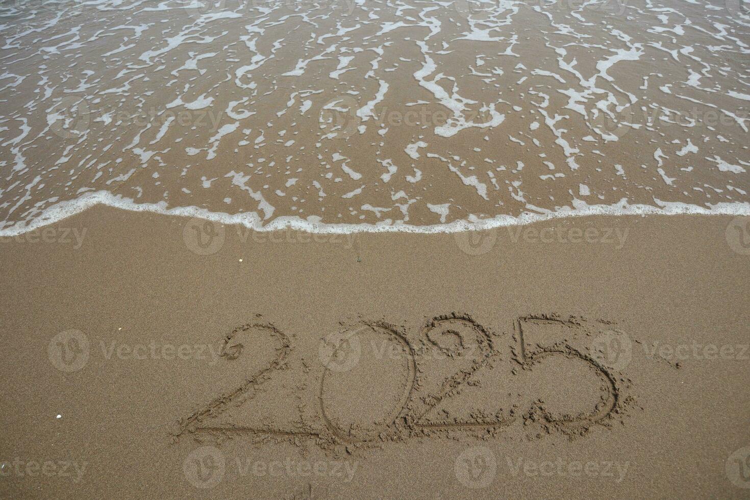New Year 2025 written in the sand on a beach with sea wave background. 24954437 Stock Photo at
