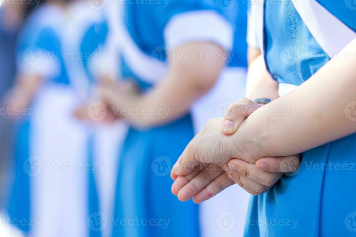 Young Thai female nursing students cross their arms behind their backs and stand in a line to celebrate senior nurses' graduation. photo