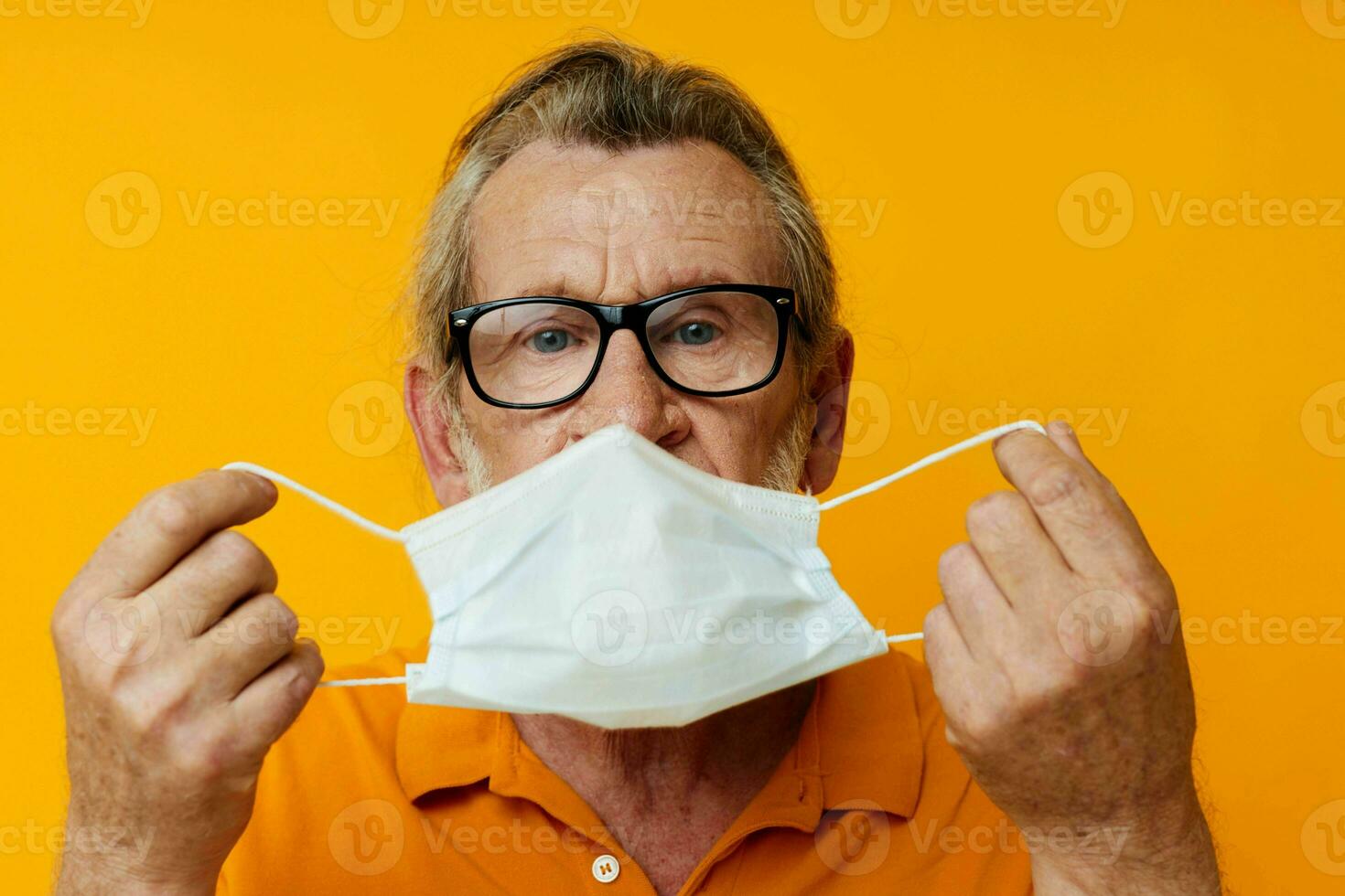 Senior grey-haired man medical mask on the face protection close-up yellow background photo