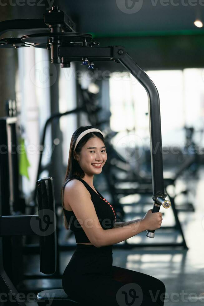 asiático deporte mujer sonriente ejercicio peso formación y rutina de ejercicio pesa máquina formación a el gimnasia. atleta niña formación fuerte y bueno salud y fuerza foto