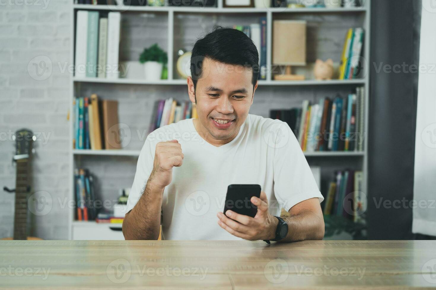 Freelance man working with laptop and mobile successful cheerful, sitting at wooden table. Pleasant happy man communicating in social network, conferrence vdo call. Business working concept. photo